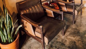 A room with two leather armchairs, a potted plant, and two framed pictures on the wall. - Taloh Homestay Chiangmai (Mae On)