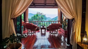 A wooden deck with two wicker chairs facing a scenic mountain view. - Taloh Homestay Chiangmai (Mae On)