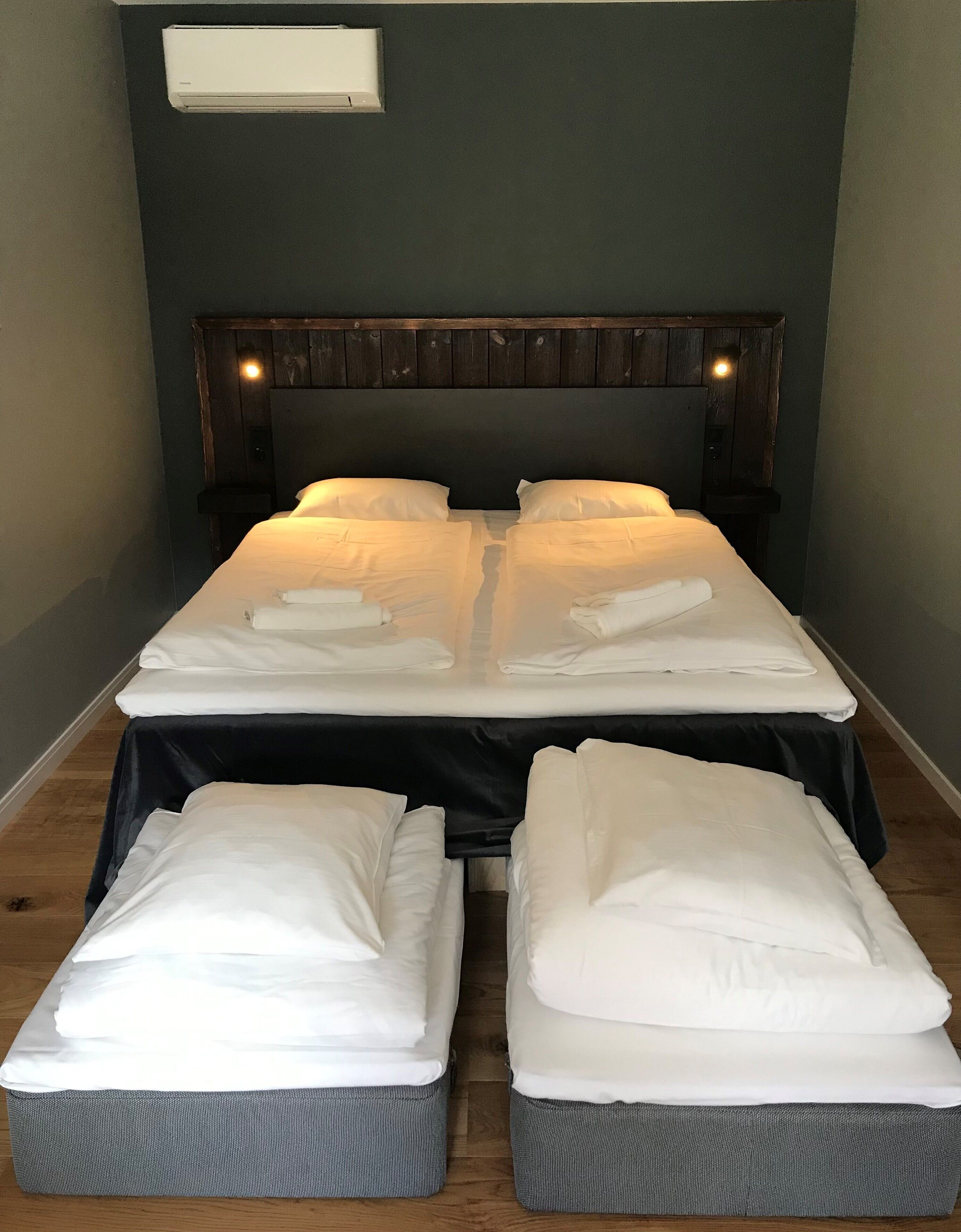 Une chambre avec un grand lit, deux tables de chevet et une tête de lit.