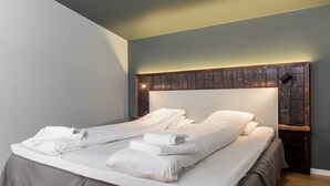 Een net opgemaakt bed met witte lakens en een houten hoofdbord met ingebouwde verlichting.