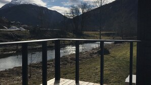 Een houten terras met uitzicht op een rivier en bergen.
