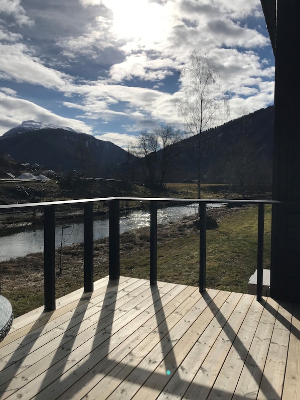 Una terraza de madera con vistas a un río y montañas.