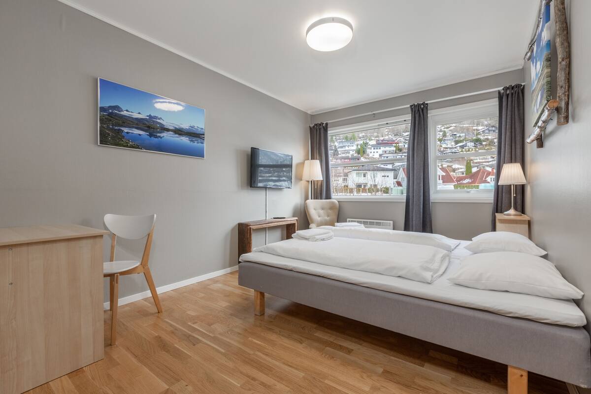 Ein modernes Hotelzimmer mit Bett, Schreibtisch, Stuhl und Fernseher.