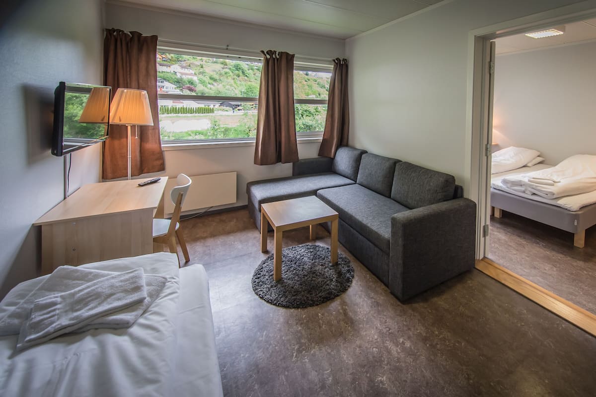 Ein Hotelzimmer mit einem Bett, einer Couch, einem Schreibtisch mit Lampe und einem Fernseher.