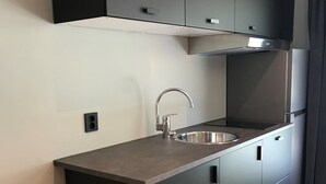 Een kleine keuken met donkere kastjes, een roestvrijstalen spoelbak en een moderne kraan.