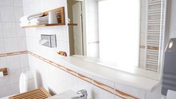 Un baño moderno con un lavamanos blanco, un espejo y un perchero para toallas.