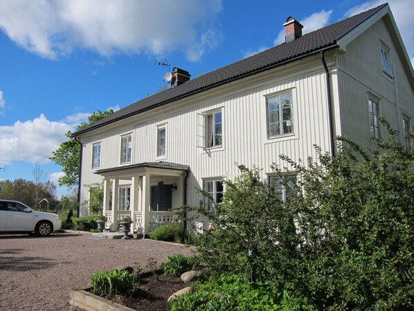 A two-story white building with a porch, a chimney, and a satellite dish. - Tössestugan Herrgårdshotell (Tösse)
