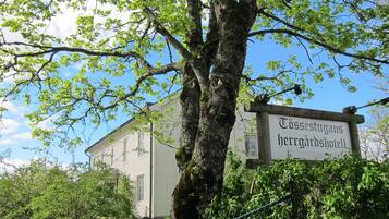 Señal para 'Tissestugans herrgårdsshotell' con un edificio al fondo.