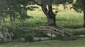 A wooden bridge over a grassy area with trees in the background.