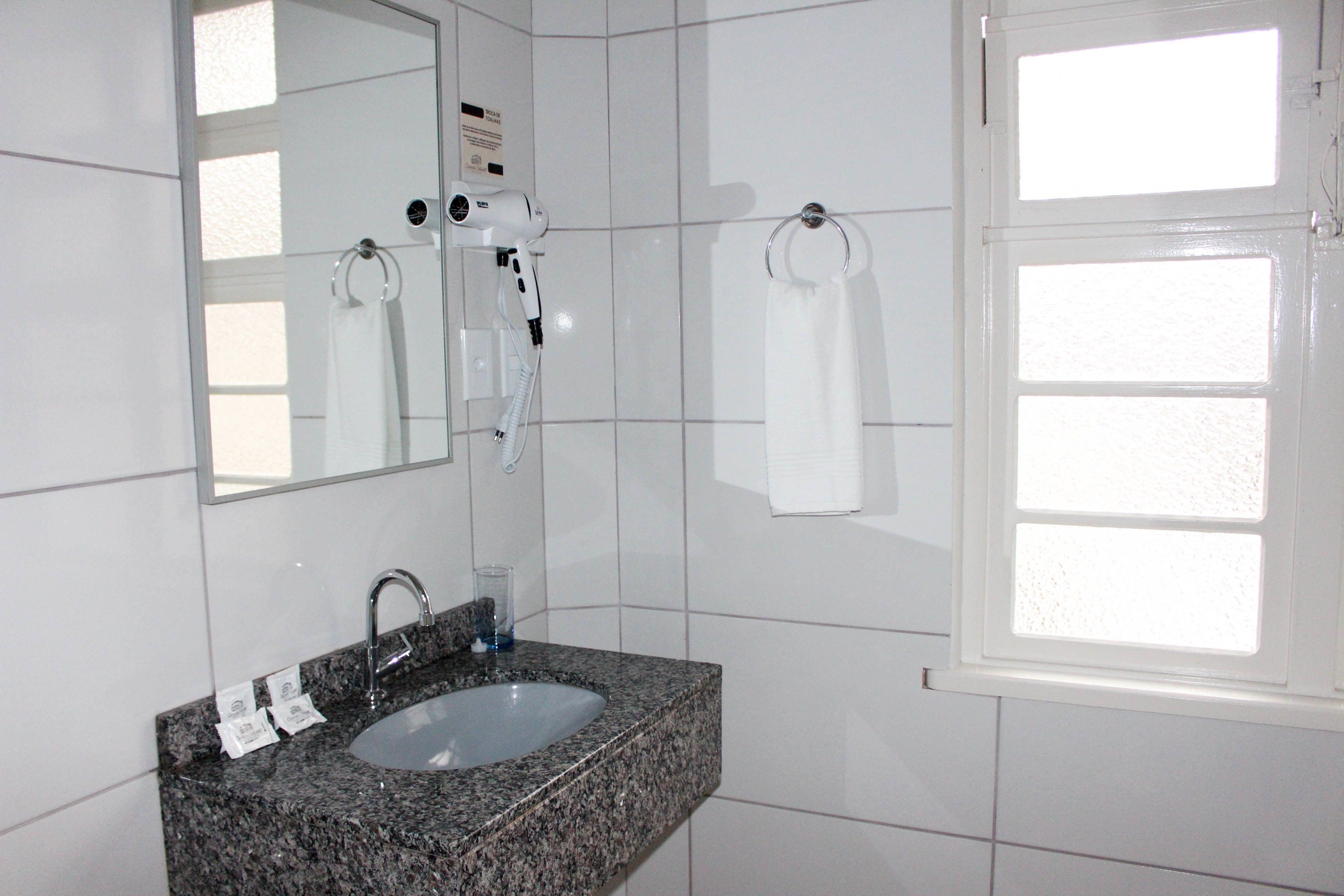 A bathroom with a granite sink, a mirror, a hairdryer, and a towel rack.