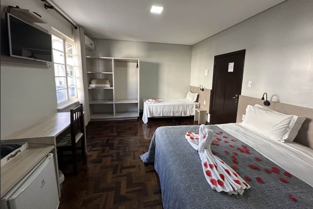 Una habitación de hotel con cama, escritorio, silla, armario y televisor.