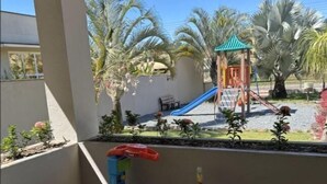 A balcony with a view of a playground, including a slide and climbing structures, and various children's toys and play equipment. - Pousada Casarão Schmidt (Pomerode)