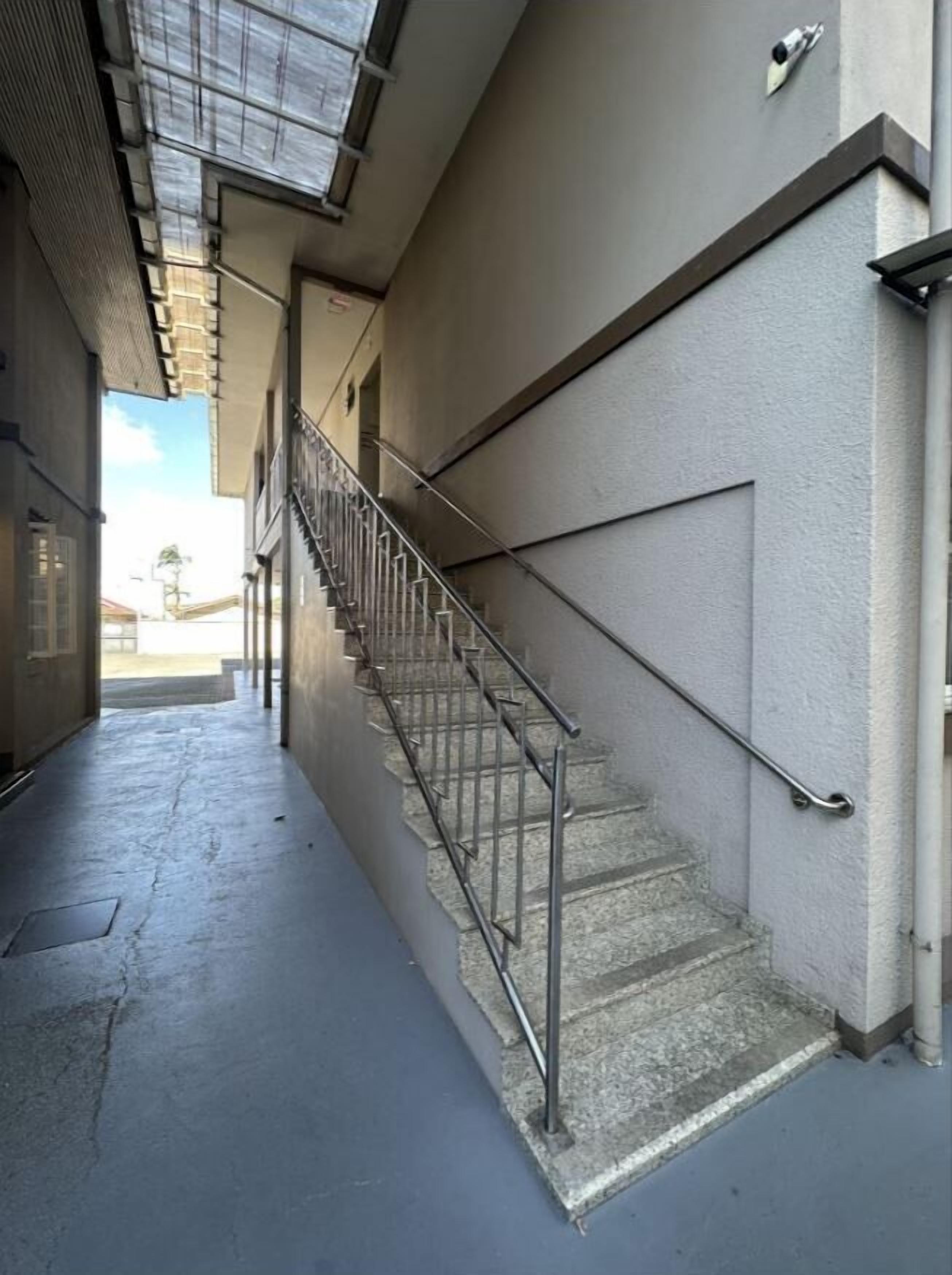 Un pasillo estrecho con una escalera metálica que sube a un piso superior.