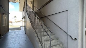 Un pasillo estrecho con una escalera metálica que sube a un piso superior.