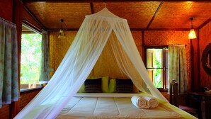 A room with a bed under a canopy, a window with curtains, and a hanging light fixture.