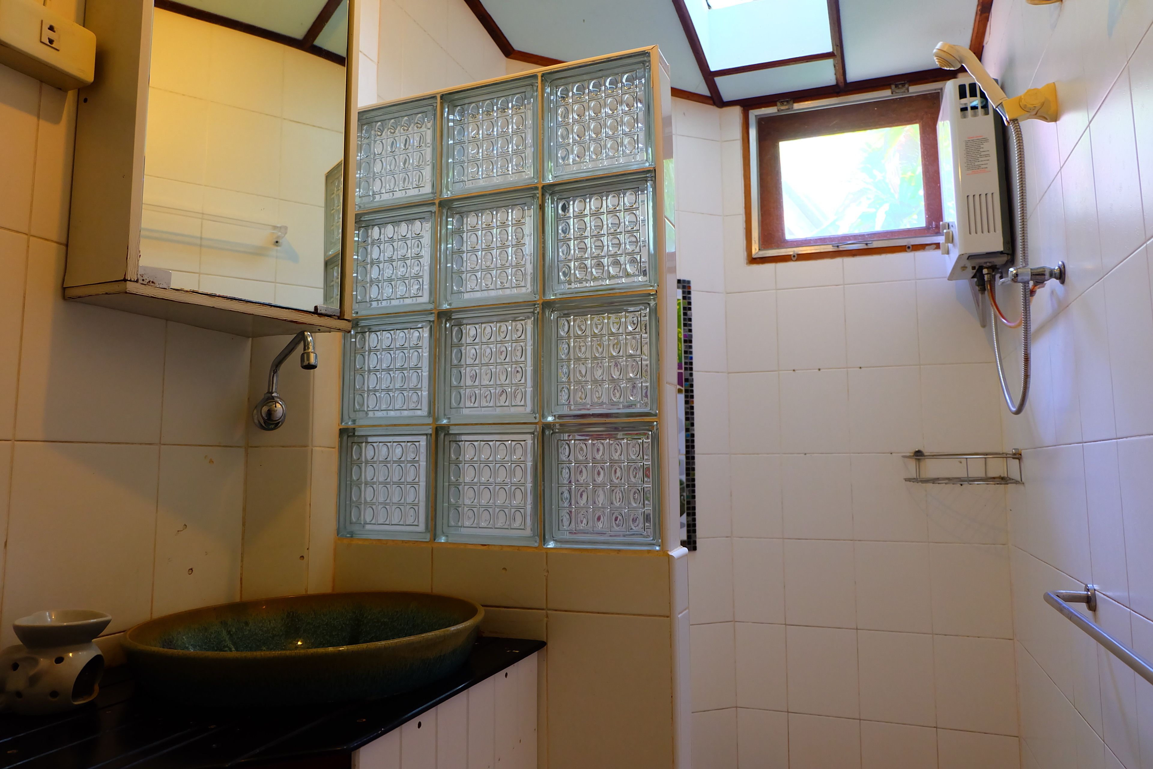 Ein Badezimmer mit Duschkabine, Waschbecken und einem Fenster für natürliches Licht.