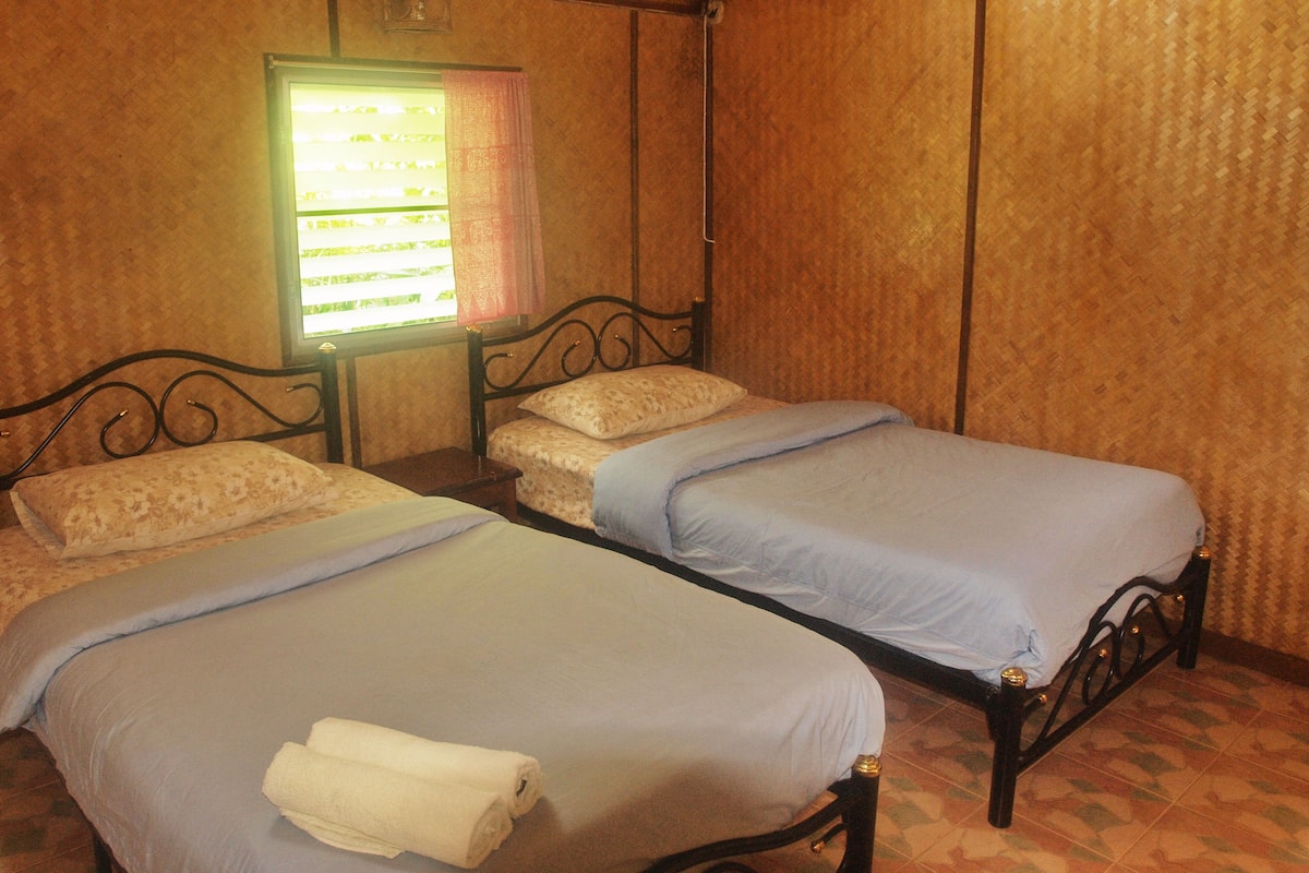 A room with two single beds, a window with a curtain, and a small table.