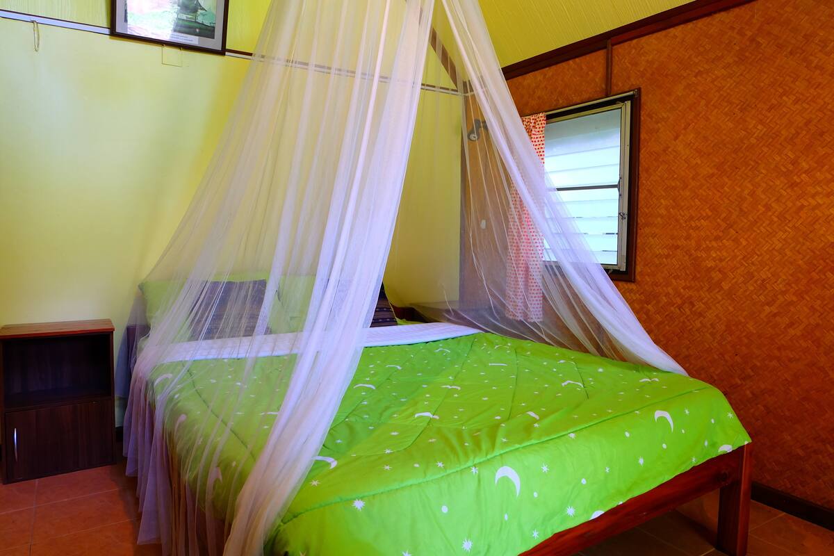 A bed with a green bedspread and white canopy.