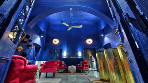 Una habitación con techo azul, ventilador de techo y sillas rojas.