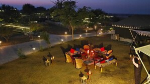 Un espacio al aire libre con mesas, sillas, una carpa y una persona de pie.