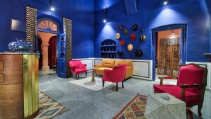Una habitación con pared azul, un armario de madera, un sofá rojo, un sofá amarillo y un sillón rojo.