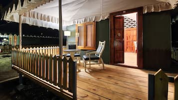 A wooden deck with a white canopy, a wooden door, and a chair.