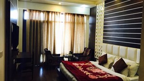 A hotel room with a bed, a desk, a chair, and a TV. - Sun N Star (Dehradun)