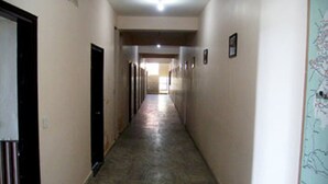 A long, narrow hallway with doors on both sides, leading to a bright room at the end. - Sun N Star (Dehradun)