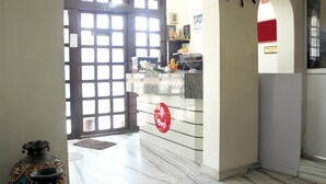 A hallway with a large wooden door, a small statue, and a wall-mounted steering wheel decoration. - Sun N Star (Dehradun)