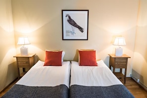 A double bed room with two nightstands, each with a lamp, and a framed bird illustration on the wall. - Nordens Ark Bed & Breakfast (Hunnebostrand)