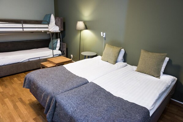 Une chambre avec deux lits, une petite table, une lampe et une prise électrique au mur.