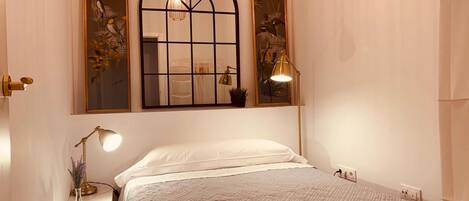 Une chambre à coucher comprenant un lit, une table de chevet, une lampe et deux miroirs fixés au mur.