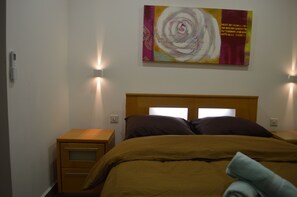 A hotel room with a bed, two bedside tables, and a wall-mounted artwork. - Pebbles Appartment (Zebbug)