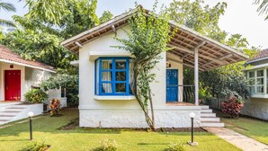 Un petit bâtiment d’un seul étage, à l’extérieur blanc, avec des touches de bleu, notamment au niveau d’une fenêtre et d’une porte.