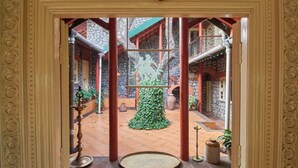 An ornate entrance with a decorative archway leading to a courtyard with stone walls, a central sculpture, and potted plants. - GuestHouser 1 BR Villa 520d (Mawal)