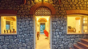A stone building entrance with a central doorway, two windows on either side, and a red chair inside. - GuestHouser 1 BR Villa 520d (Mawal)
