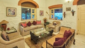 A living room with two sofas, a coffee table, and a patterned rug. There are windows with arched tops and artwork on the walls. - GuestHouser 1 BR Villa 520d (Mawal)
