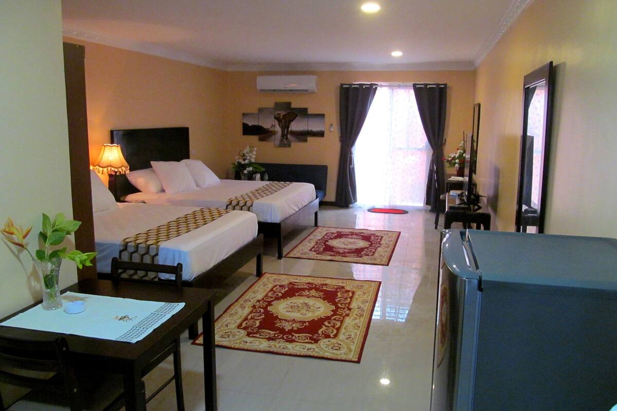 A hotel room with two beds, a desk, a chair, a TV, and a window with curtains.