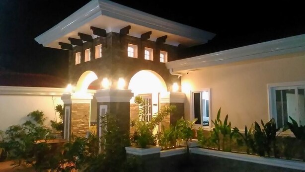 A modern building with a central tower, arched entrance, and illuminated windows. - Venezia Suites Resort (Panglao)