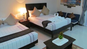 A hotel room with two beds, a sofa, a nightstand with a lamp, a small table with a vase, and a wall-mounted air conditioner. - Venezia Suites Resort (Panglao)