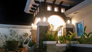 A building with a prominent arched entrance, stone pillars, and a well-lit facade. - Venezia Suites Resort (Panglao)