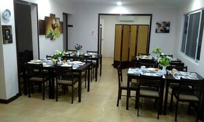 A dining area with multiple tables set for meals, chairs, and a clock on the wall. - Venezia Suites Resort (Panglao)