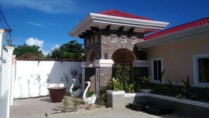 A two-story house with a red roof, stone facade, and a gated entrance. - Venezia Suites Resort (Panglao)
