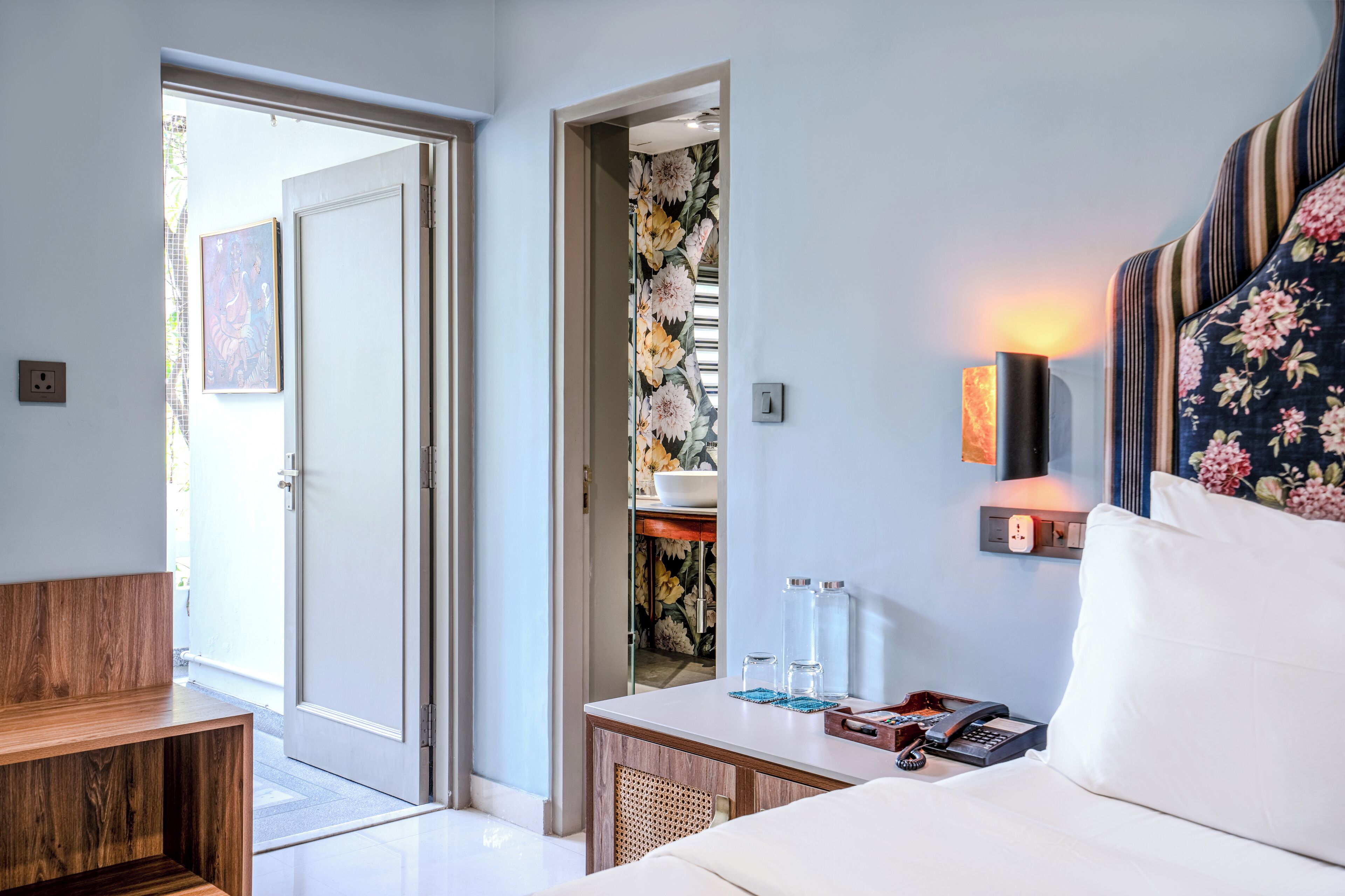 Quarto de hotel com cama, mesa de cabeceira e vista para o exterior.