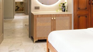 A bedroom with a bed, wooden cabinets, a round mirror, and a plant.