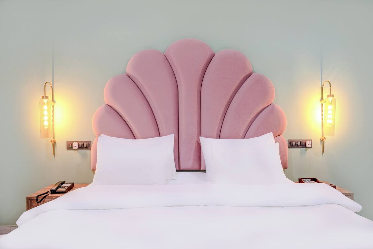 A bed with a unique scalloped headboard, white bedding, and bedside lamps.