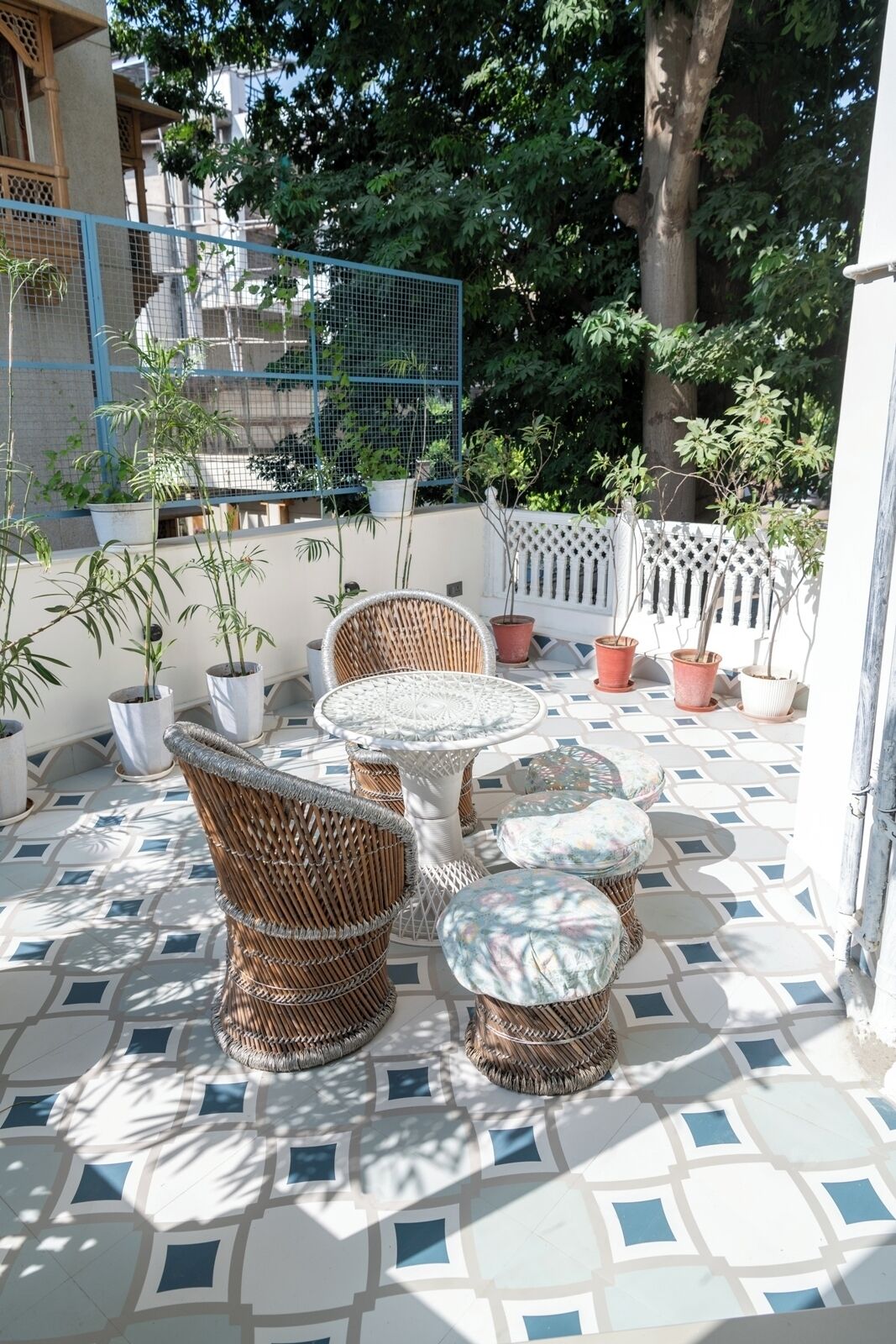 A patio area with wicker furniture, potted plants, and a patterned tile floor.