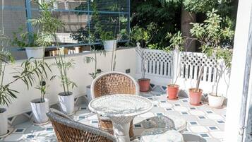 A patio area with wicker furniture, potted plants, and a patterned tile floor.