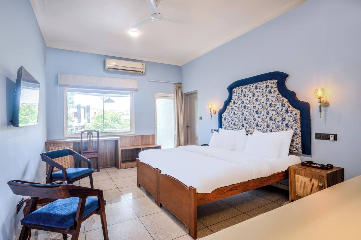 A bedroom with a wooden bed, a desk, two chairs, and a window.