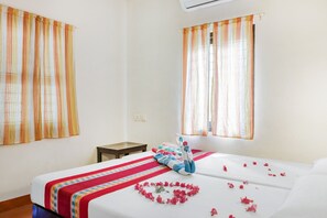 A hotel room with a bed, a small table, and two windows with curtains. - GuestHouser 1 BR Villa b529 (Cherthala)